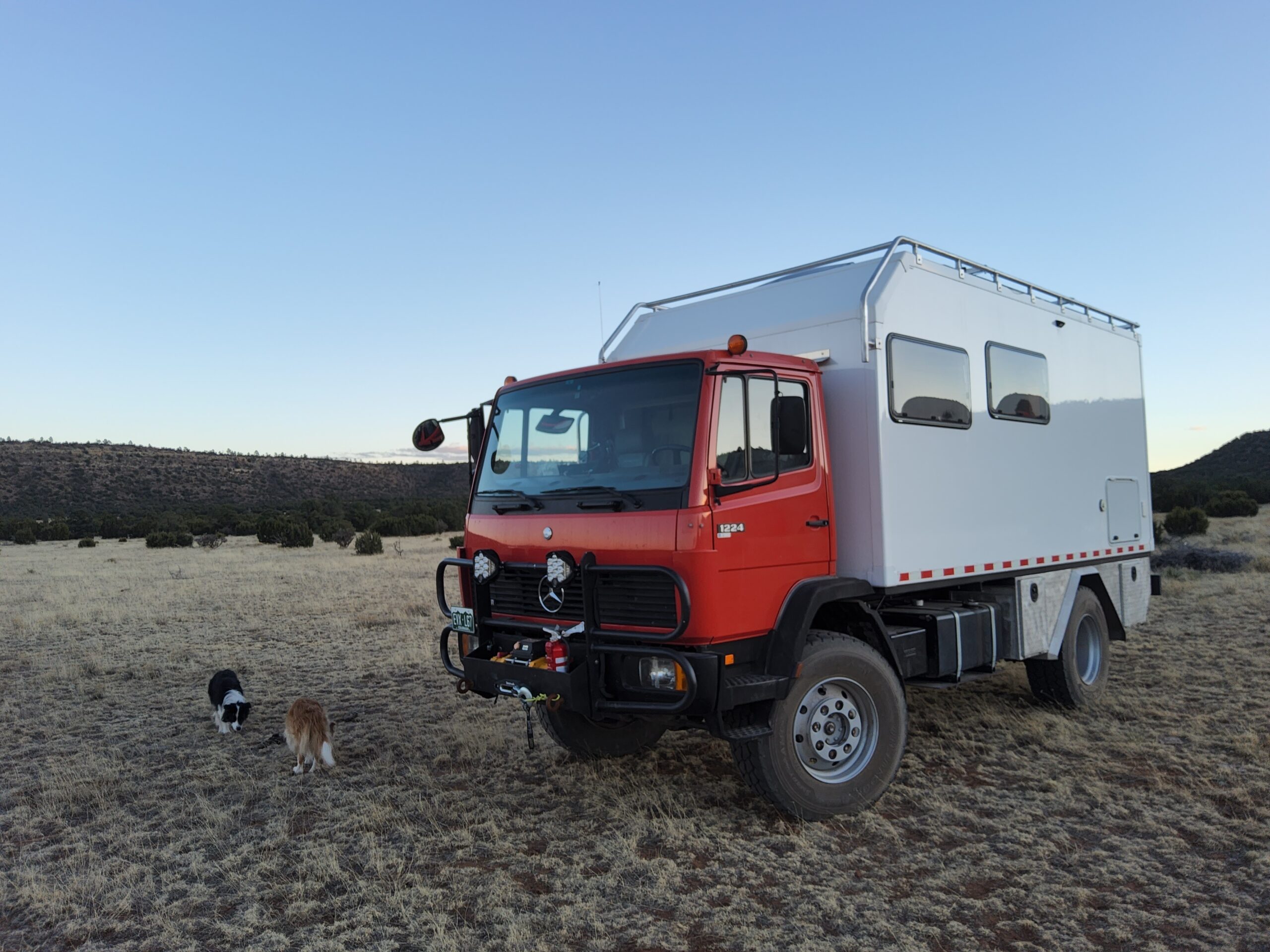 Our red Mercedes expedition truck and white camper, with our three Border Collies beside it